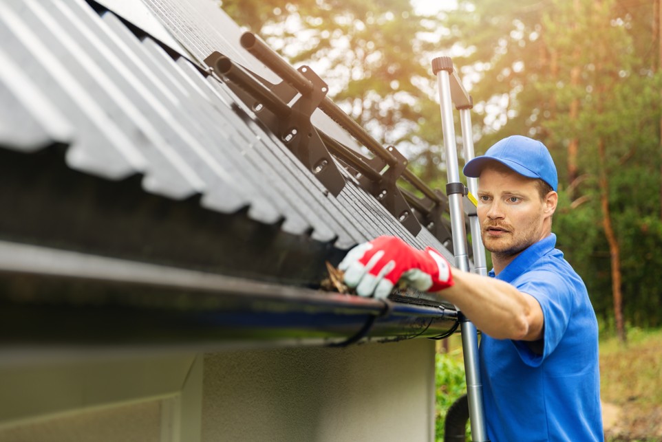 Gutter cleaner removing debris from a residential roof gutter.